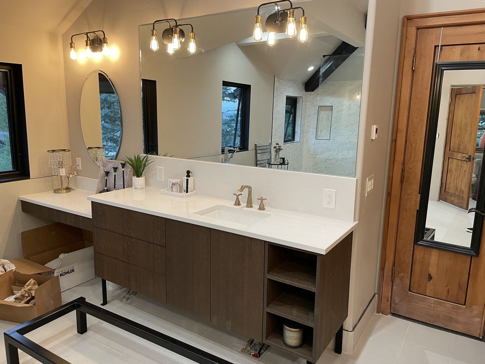 Primary bathroom double vanity with warm wood cabinetry